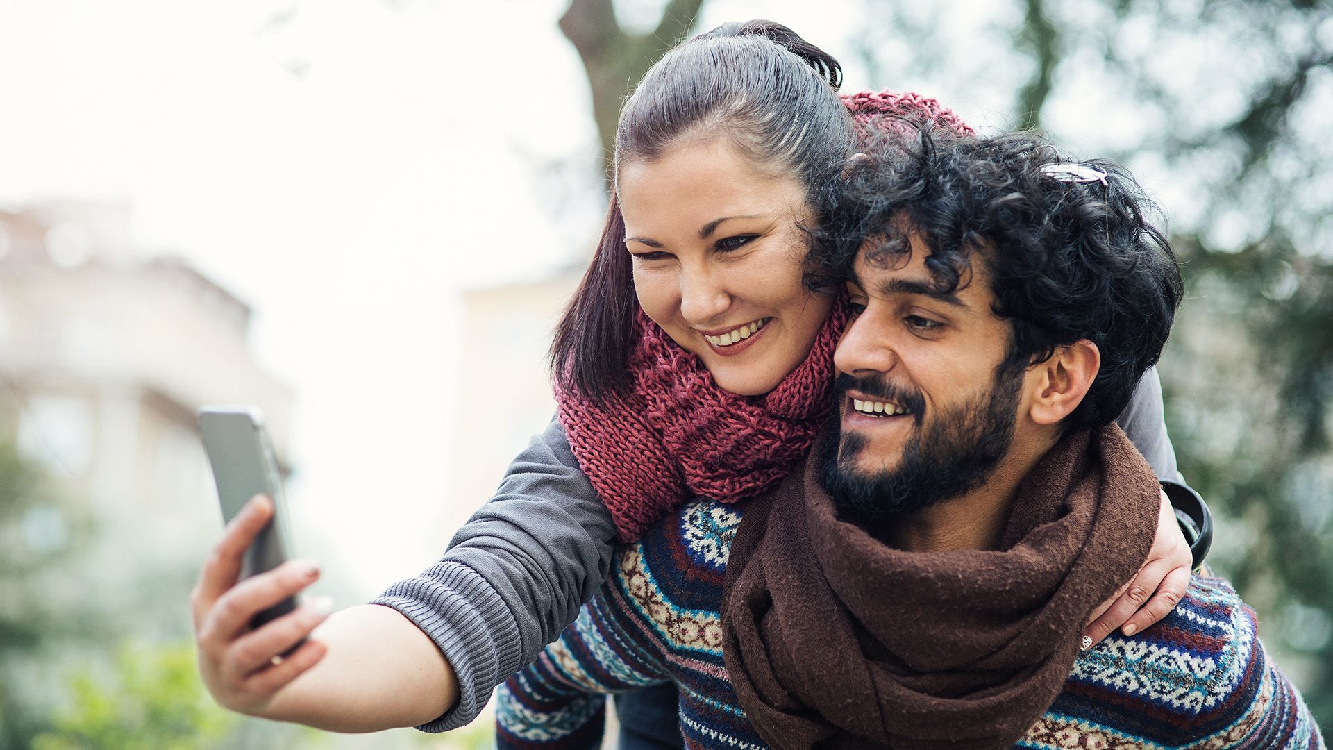 A Middle Eastern couple smiling while taking a selfie photo. 