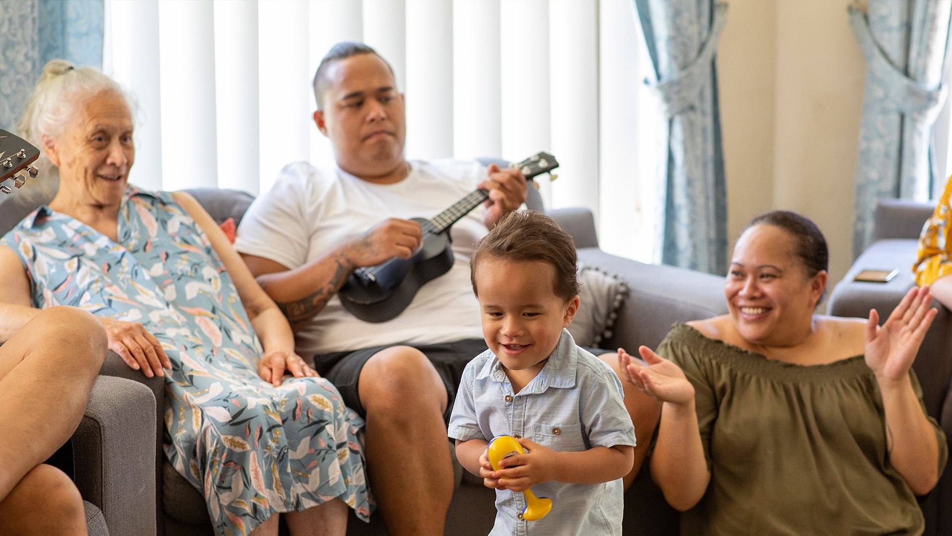A man playing an instrument while lounging with his family. 