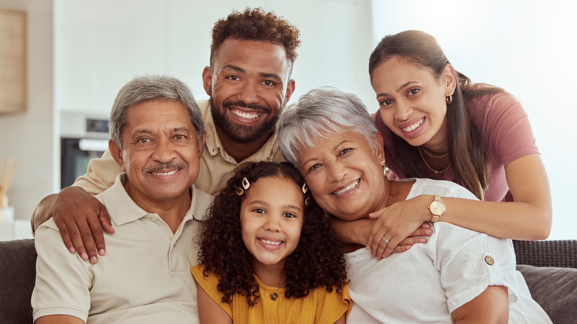 A multigenerational Hispanic family sitting together and smiling. 
