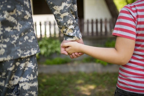 Soldier holding a child's hand.