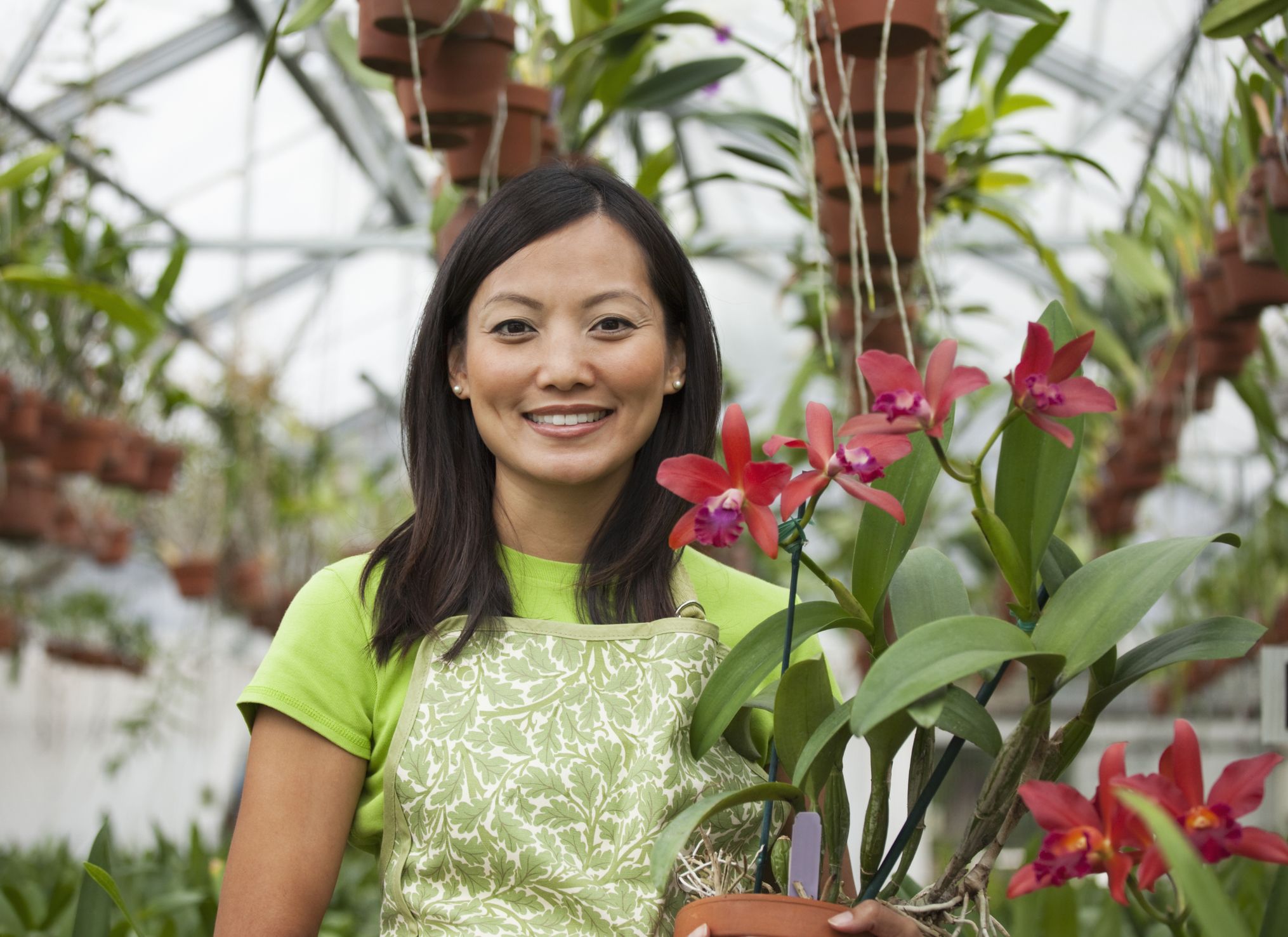 A woman is holding flowers in a greenhouse.