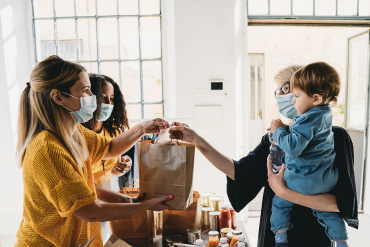 People wearing masks holding a bag of goods