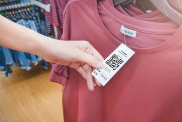 A person holding a price tag on a piece of clothing